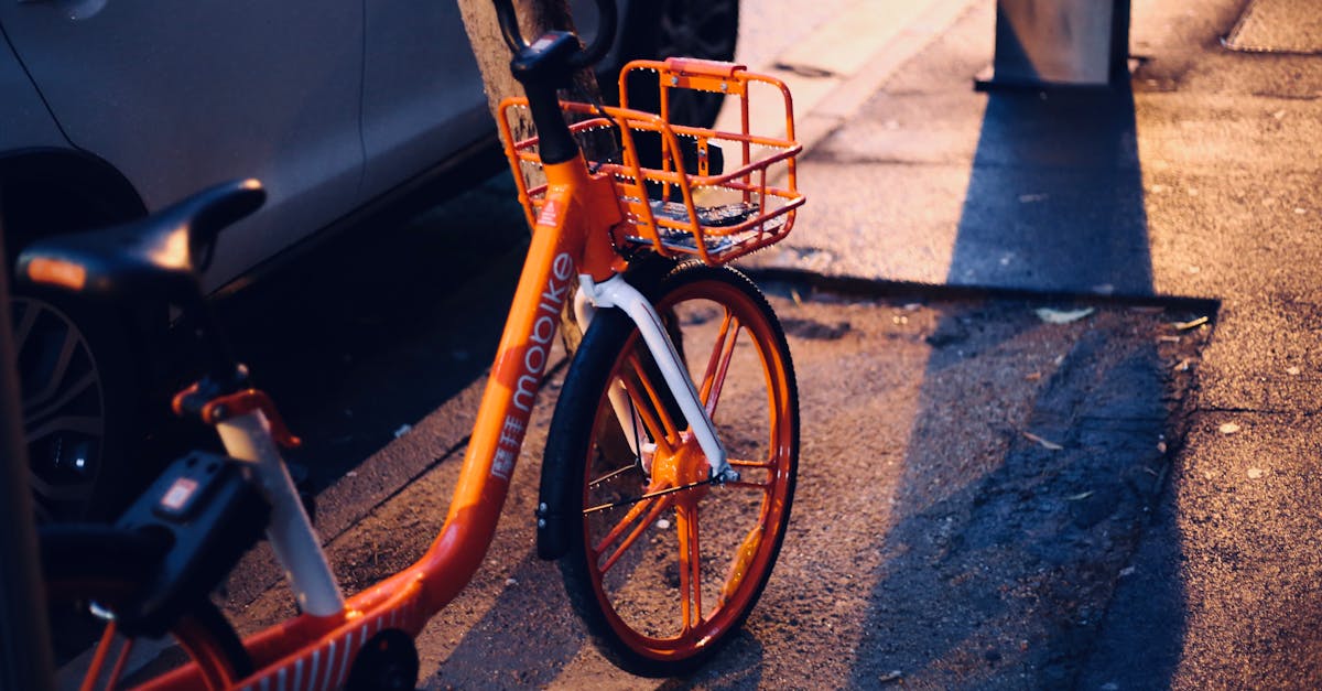 Bright orange bike parked on city street during dusk with reflections on wet pavement.